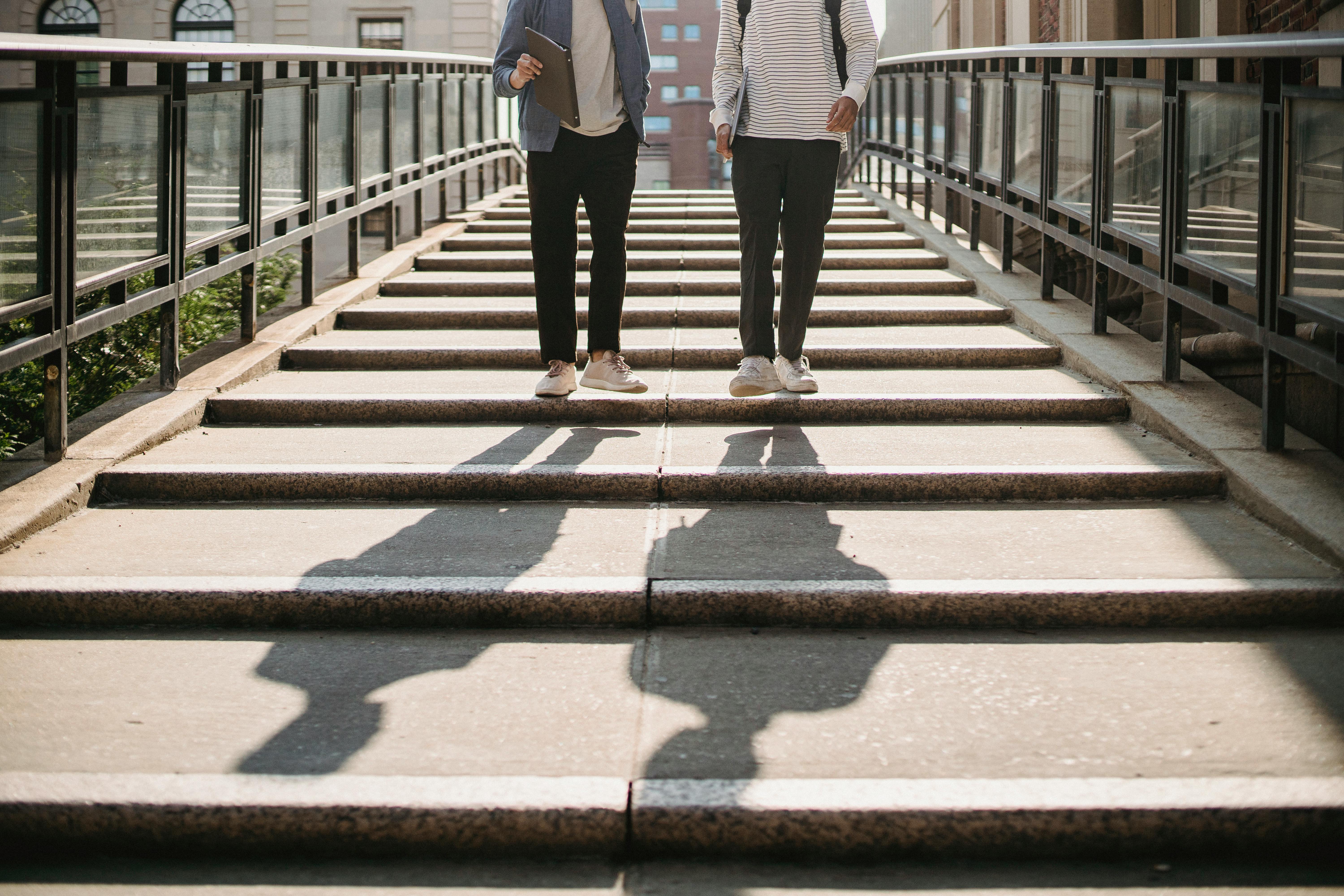 Two individuals walking down a stepped path