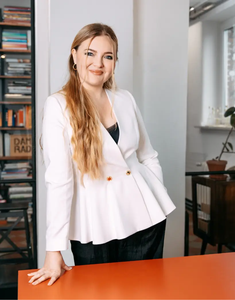 Portret kobiety w białej marynarce przy pomarańczowym stole