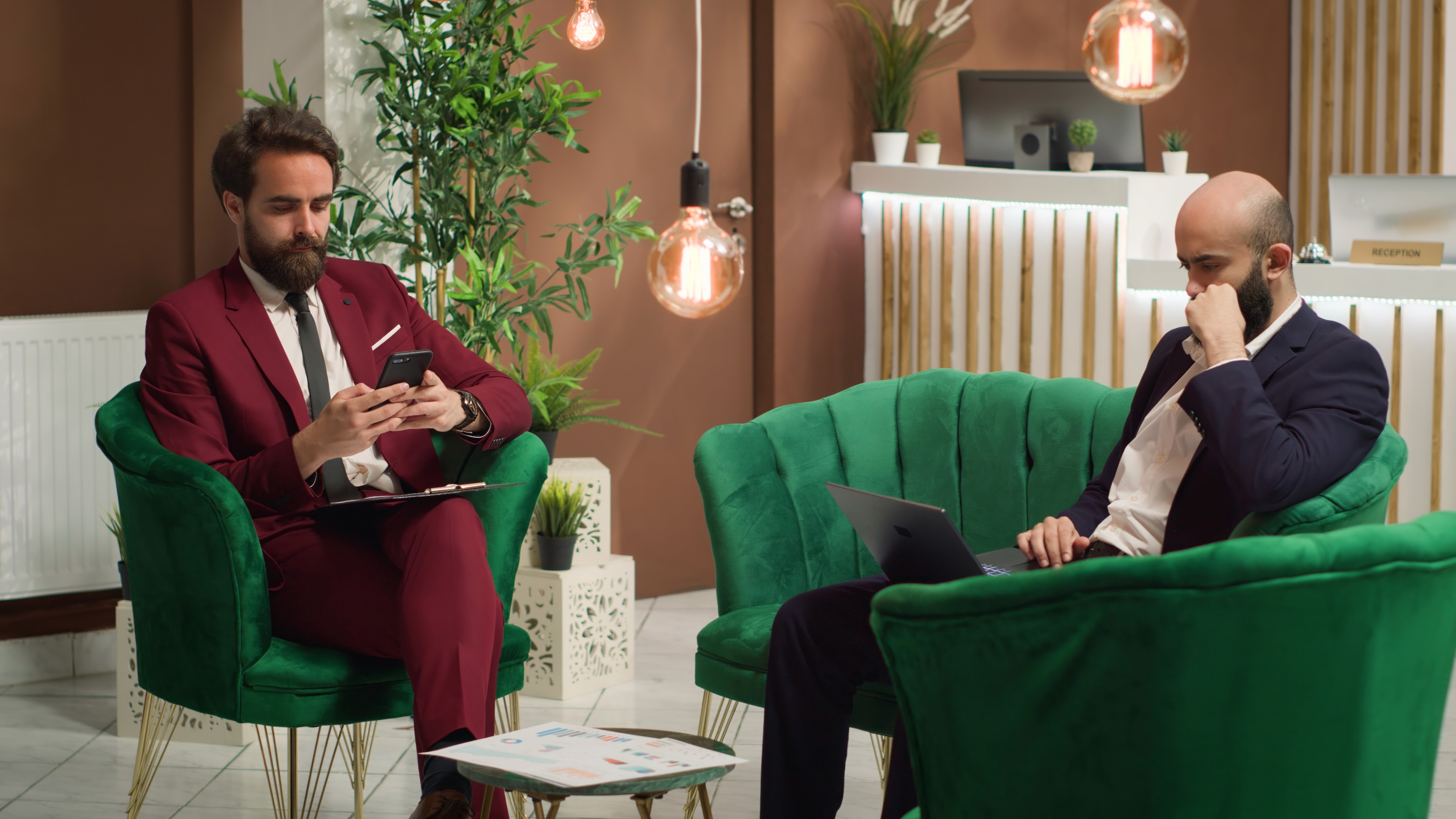 Two professional men working on devices in a modern lounge.