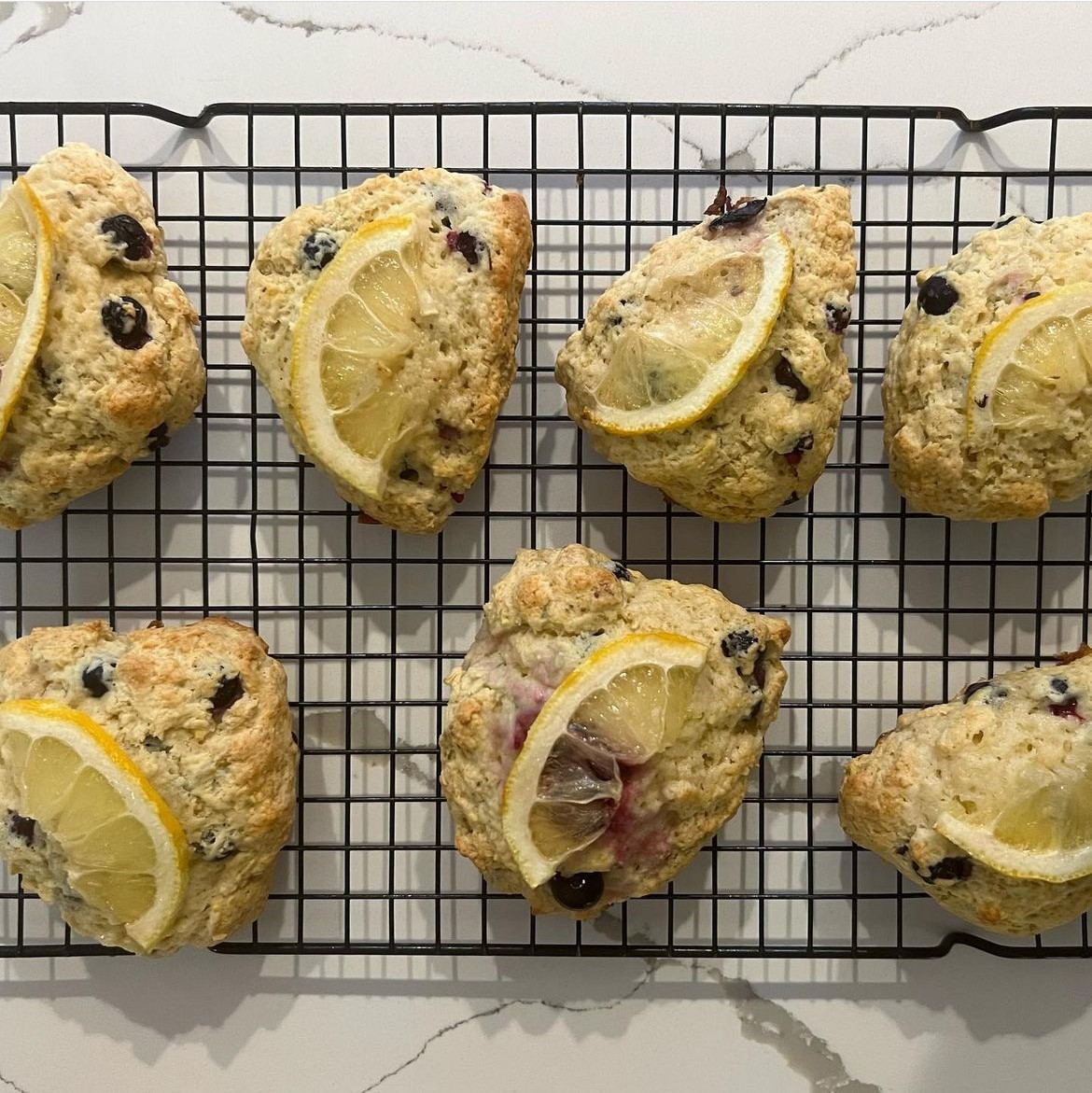 Lemon and blueberry scones with icing on a cooling rack