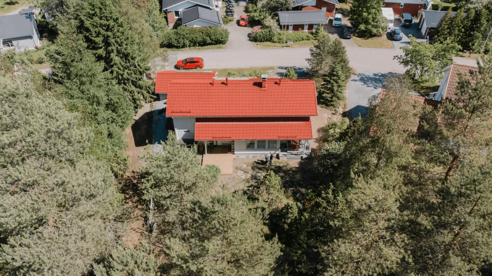 Tiilitalon ulkokuva, vihreä piha ja sininen taivas