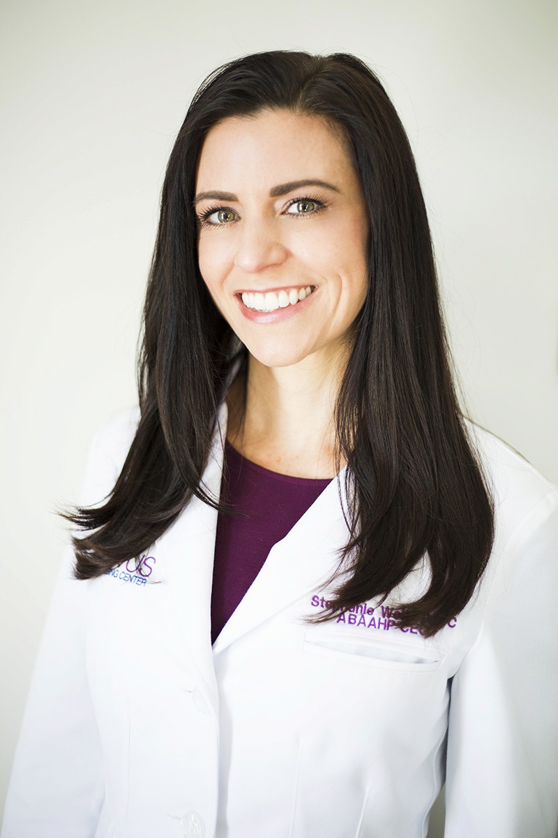 Man in glasses wearing a grey suit and blue tie, looking calmly at the camera.