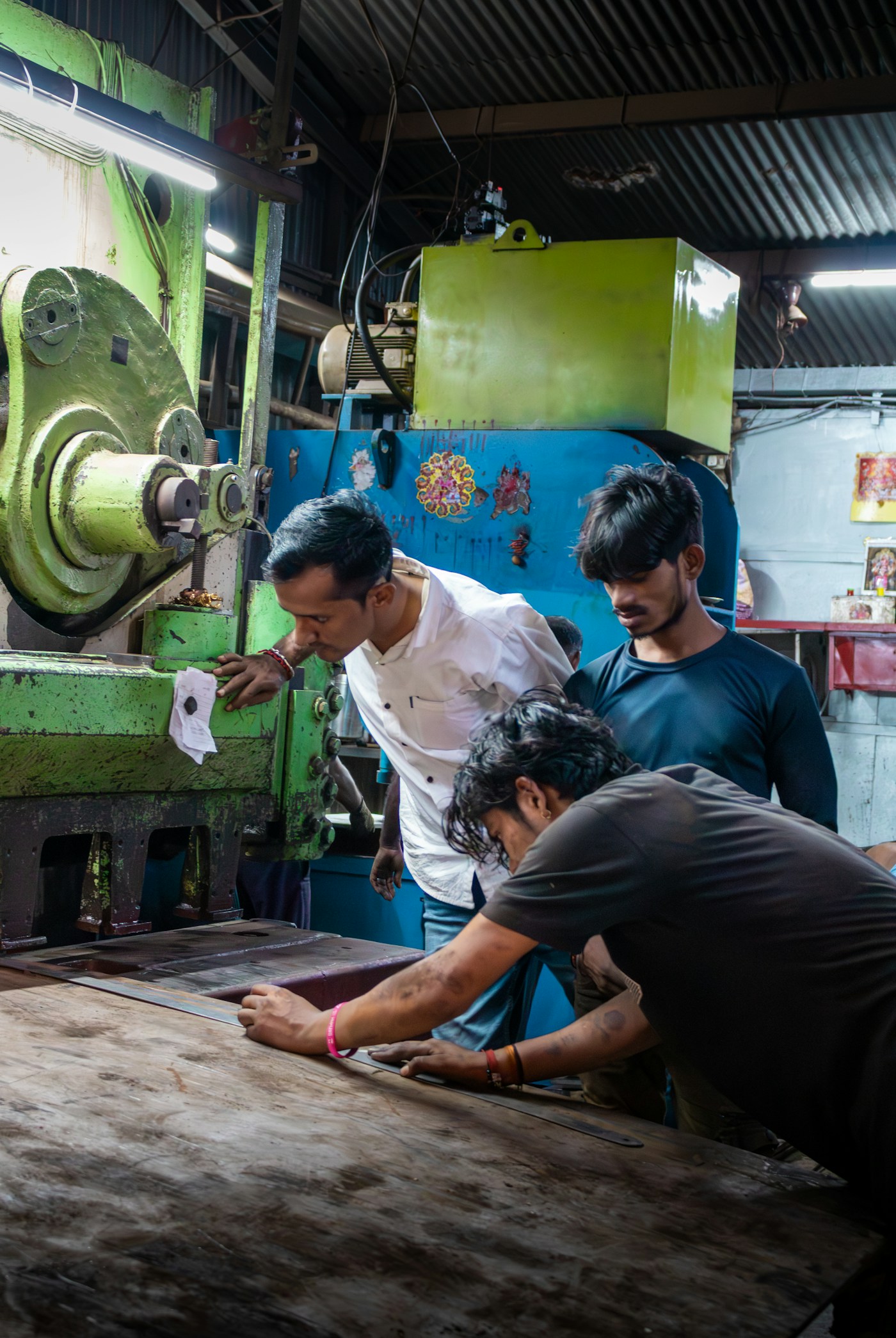 Team of Indian factory workers troubleshooting a machine together on the shop floor