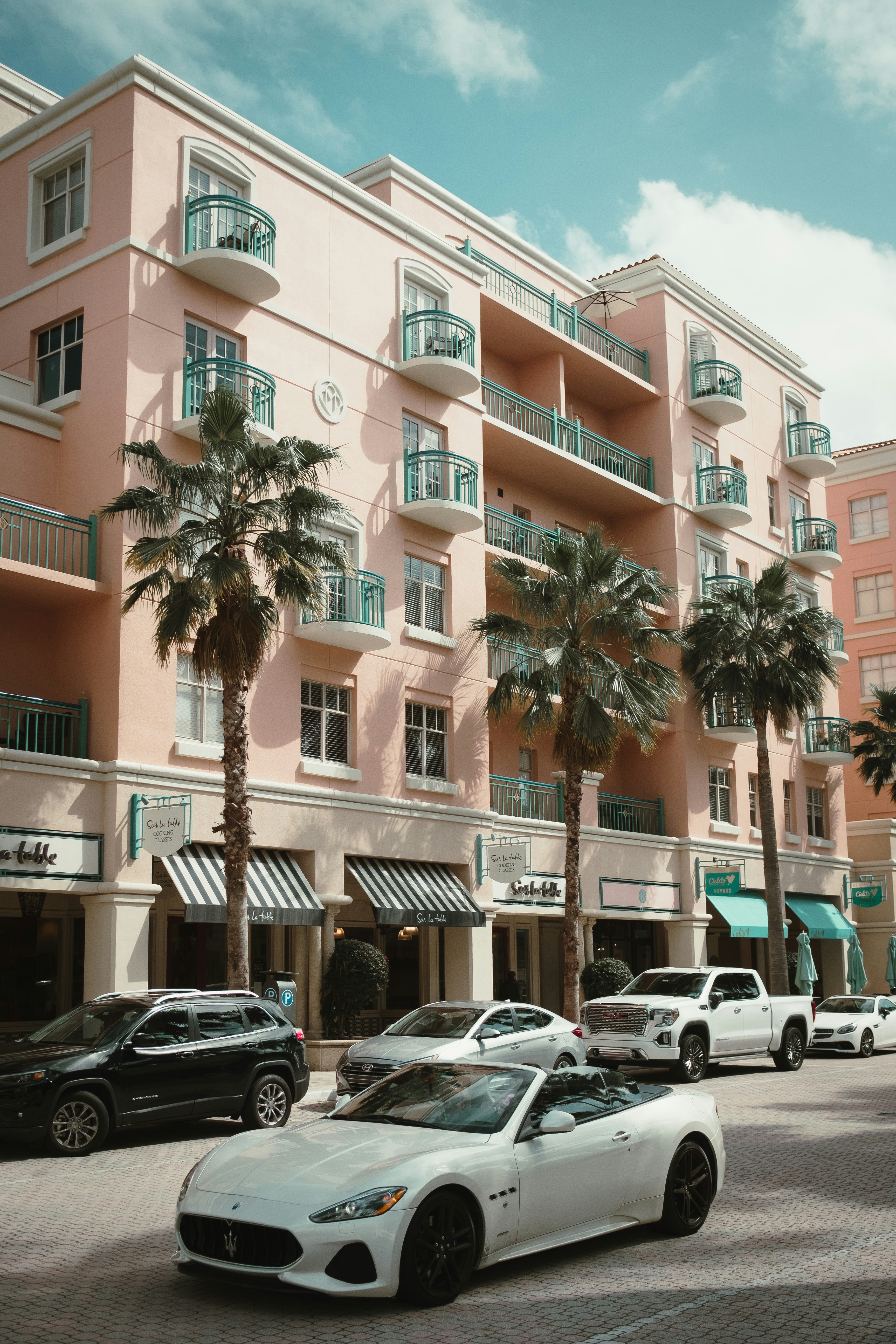 a white sports car parked in front of a pink building