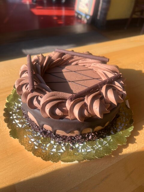 A small chocolate cake with piped frosting.