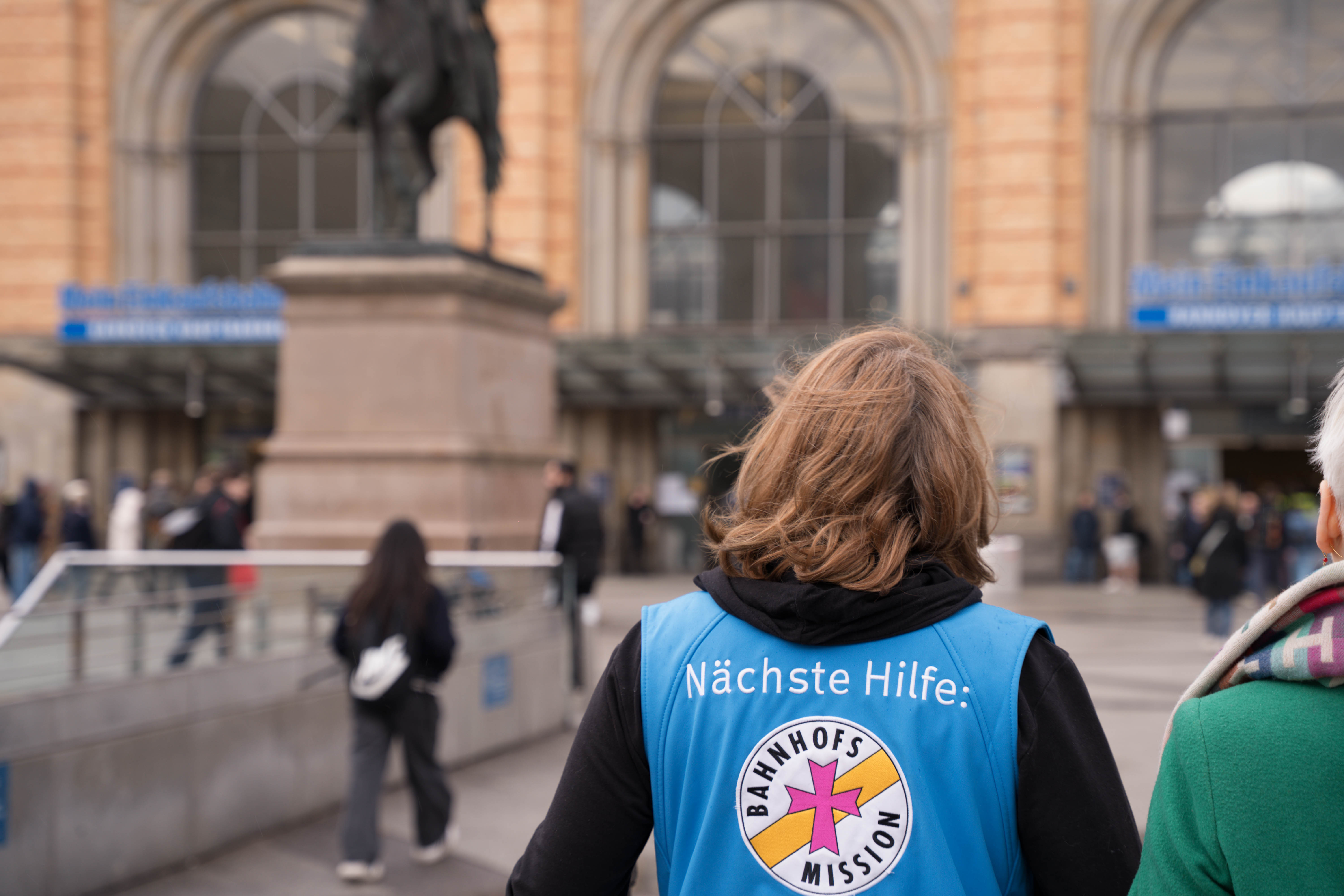 Mitarbeiterin der Bahnhofsmission Hannover hilft hilfesuchender Person am Hauptbahnhof