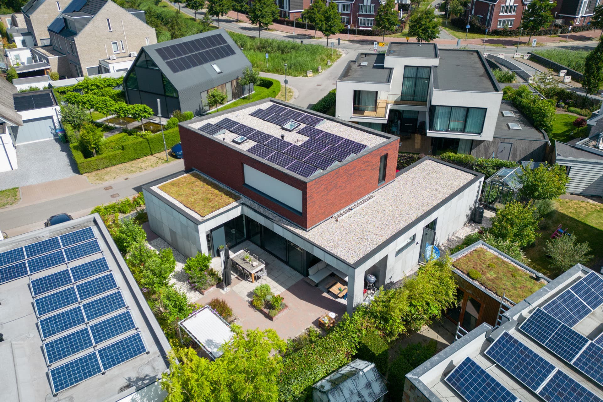 Luchtfoto van Villa Rijswijk met zonnepanelen, sedumdak, tuin en omliggende woonwijk.