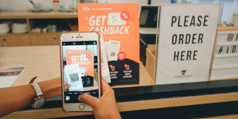 A person scanning a receipt to redeem cashback at a restaurant on the phone.