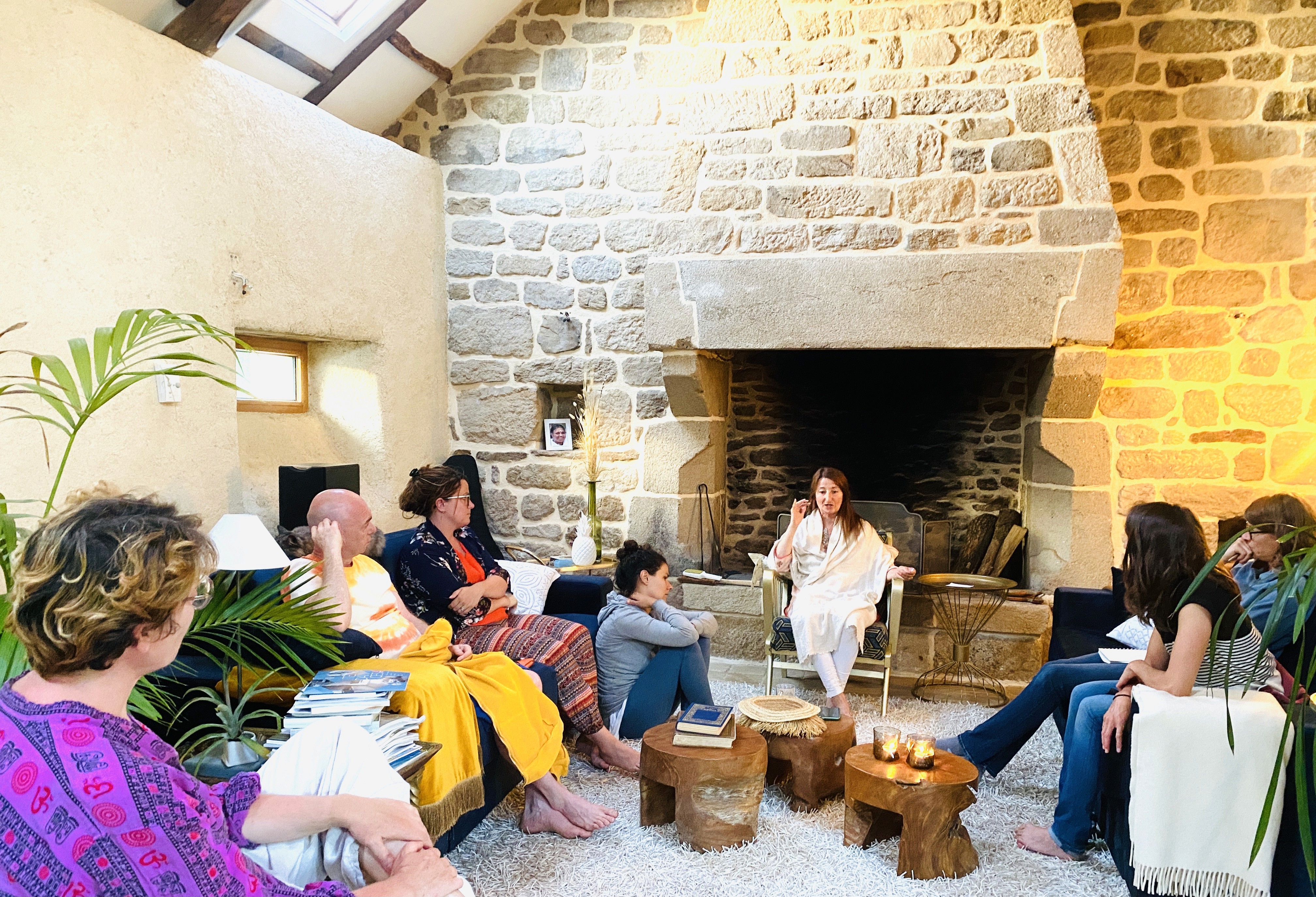 Plusieurs personnes assises dans un salon en train d'écouter une autre personne parler.