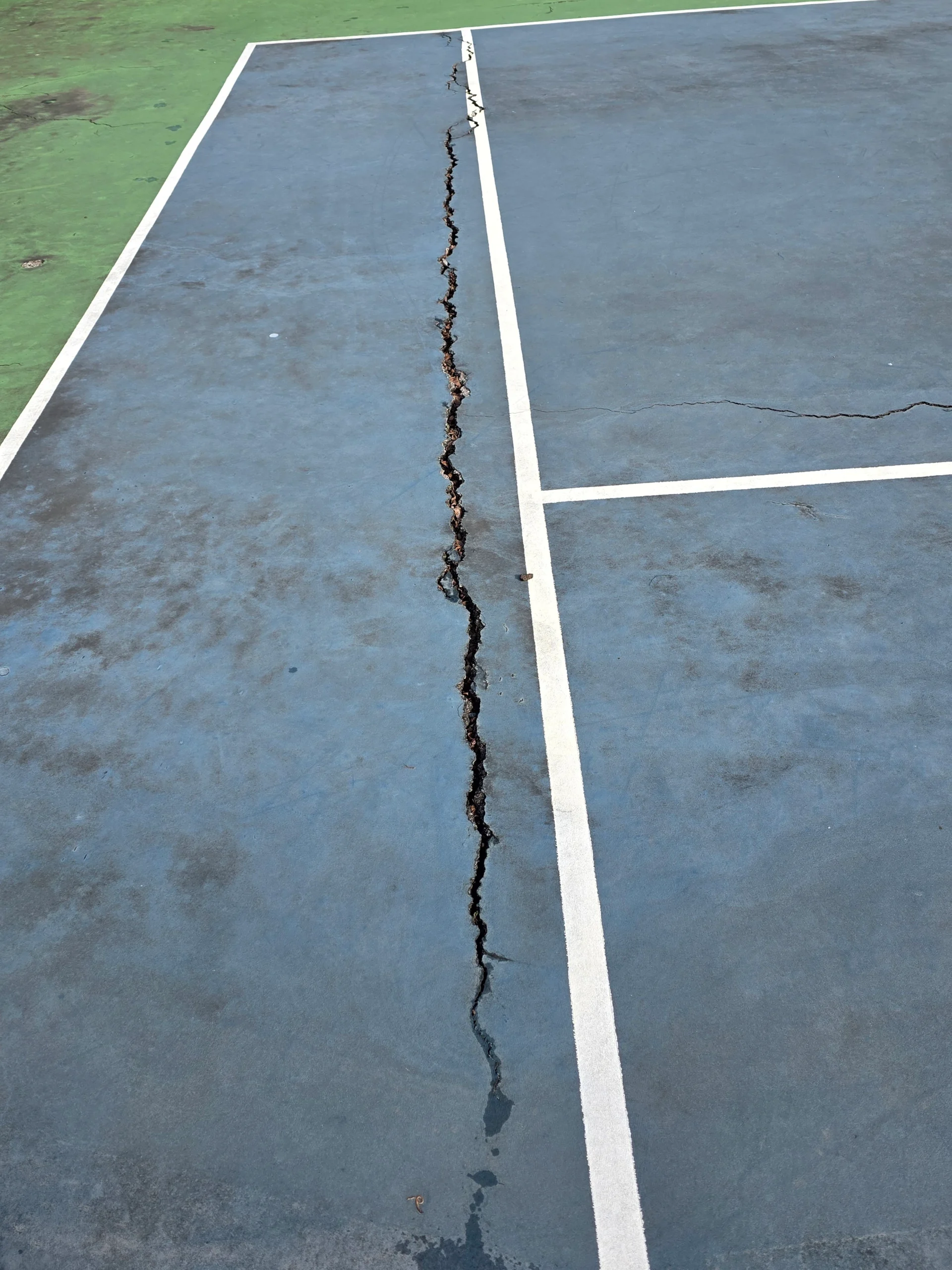 Long surface crack crossing the baseline before resurfacing at Weston Ranch apartments in Madison, AL