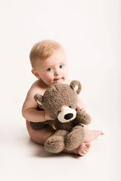 Baby sitting beside a large brown teddy bear
