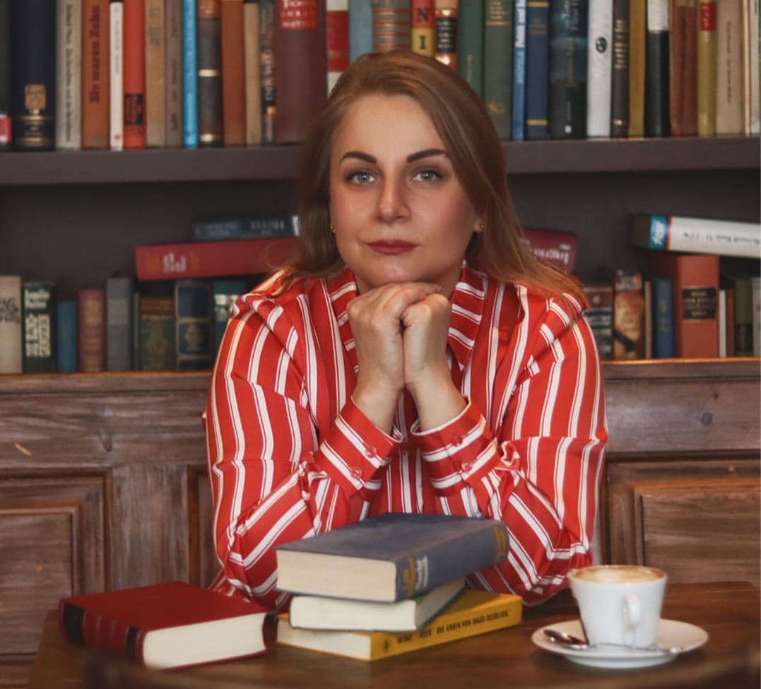 Black-and-white portrait of a man with an afro in motion, wearing a hoop earring and chain necklace, against a light gray background.