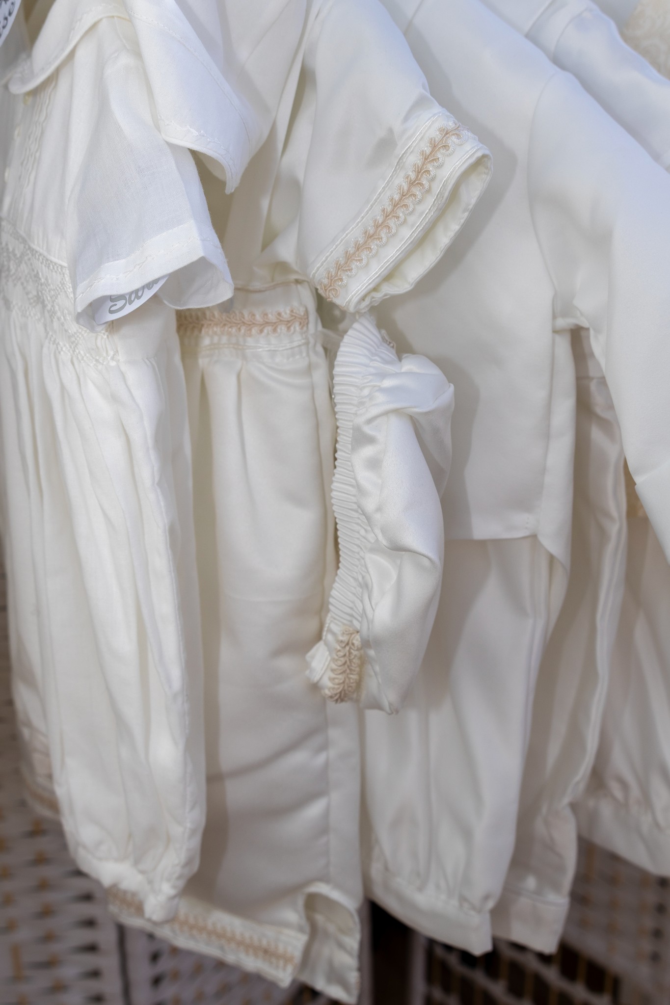 A couple in wedding attire walks hand in hand across a sunlit field.