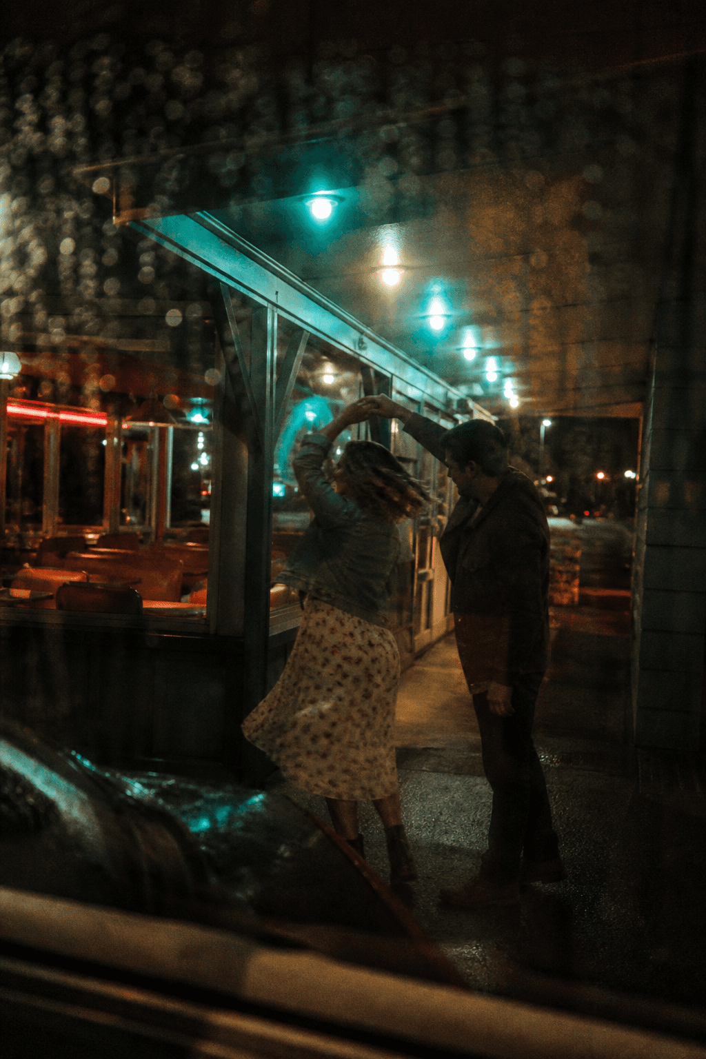 Couple embracing at night seen through a rain-streaked window