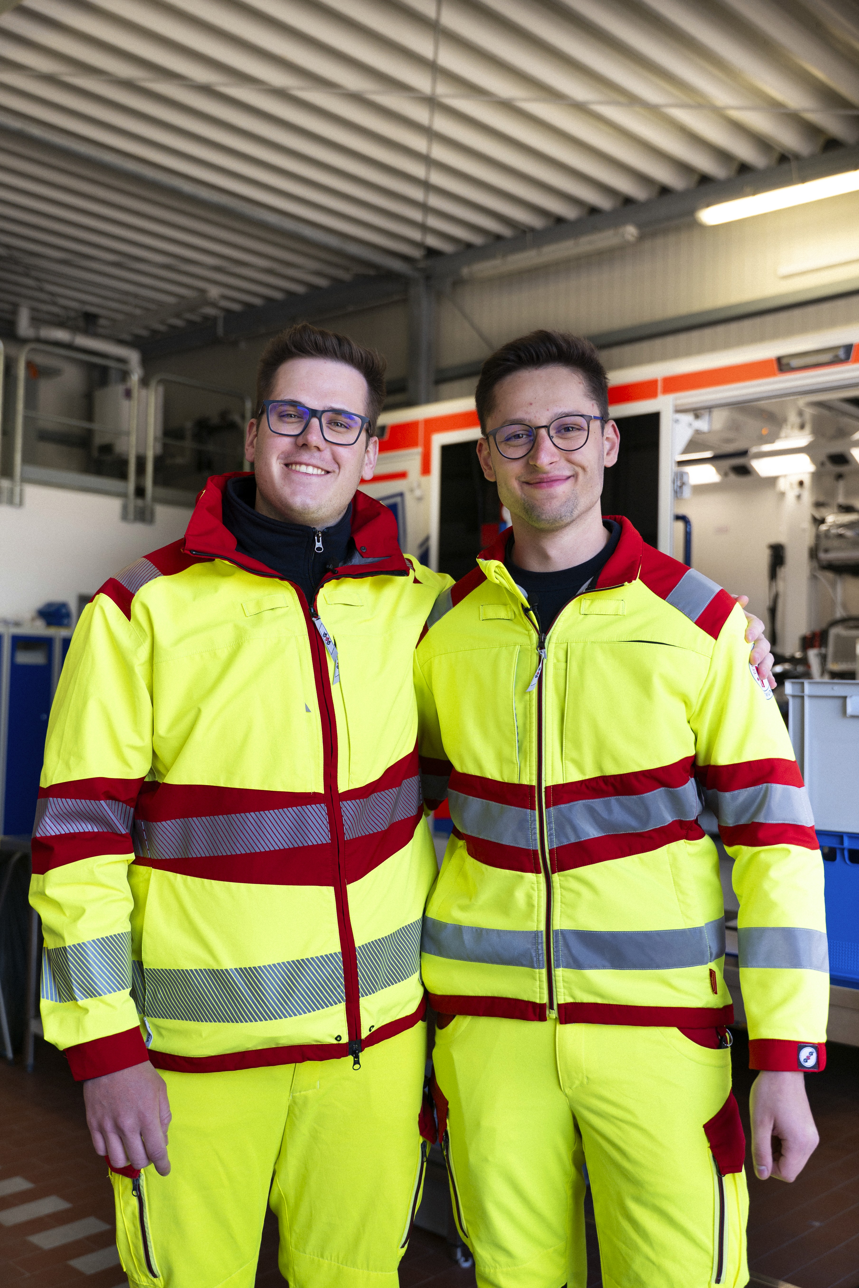 2 Notärzte in Uniform hinter einem Krankenwagen