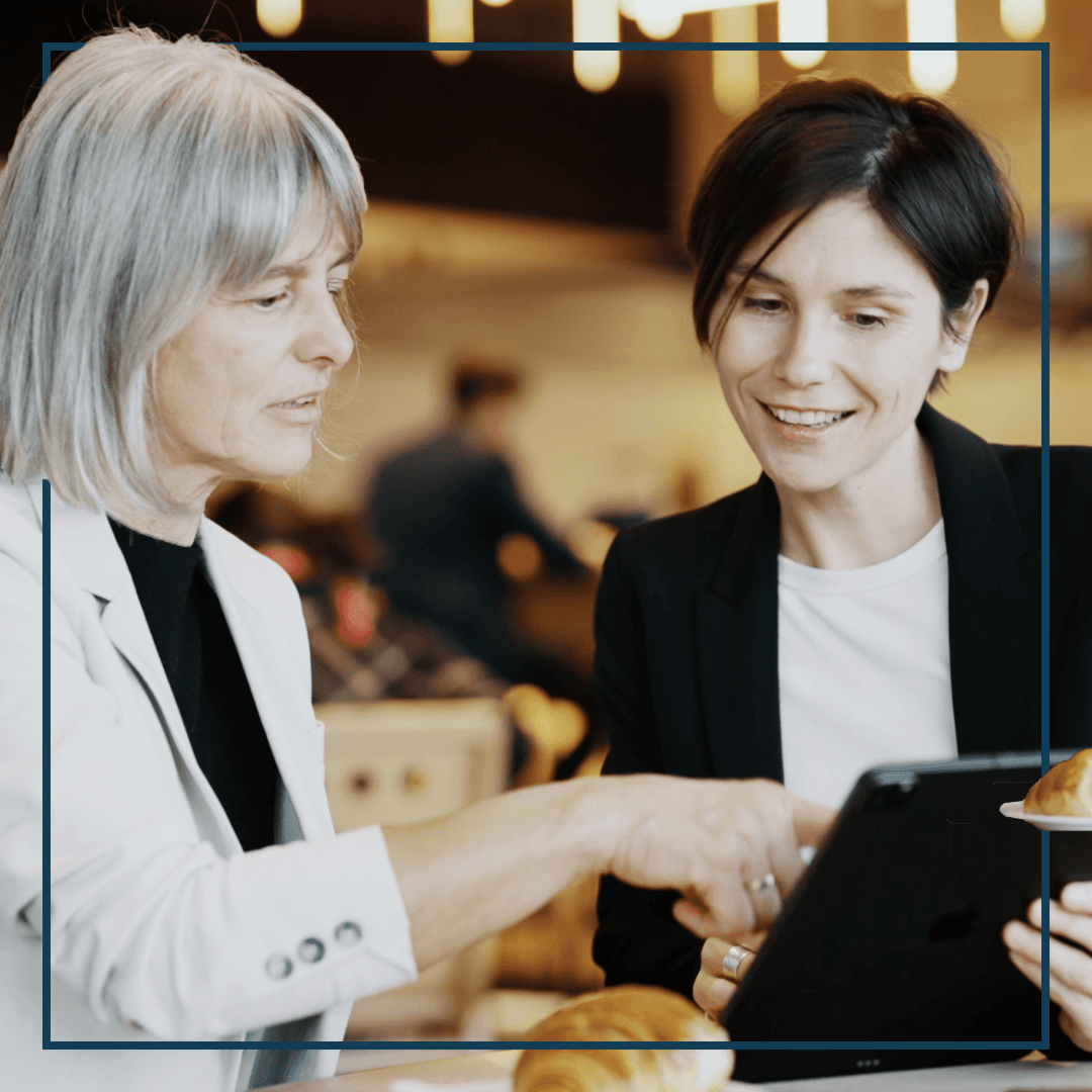 Zwei glückliche Frauen deuten aufs Tablet