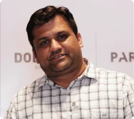 a smiling man sitting on a couch in a living room