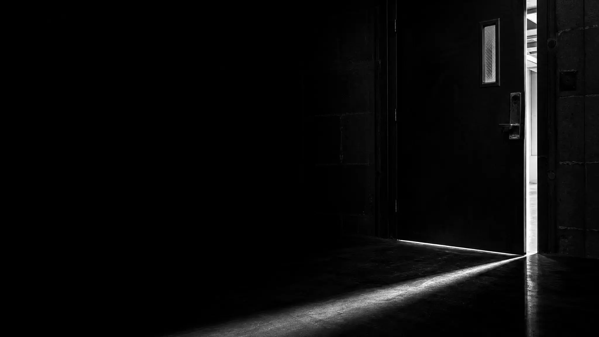 Porte entrouverte laissant passer la lumière dans un couloir sombre, symbole de la reprise d'entreprise en difficulté à la barre du tribunal.