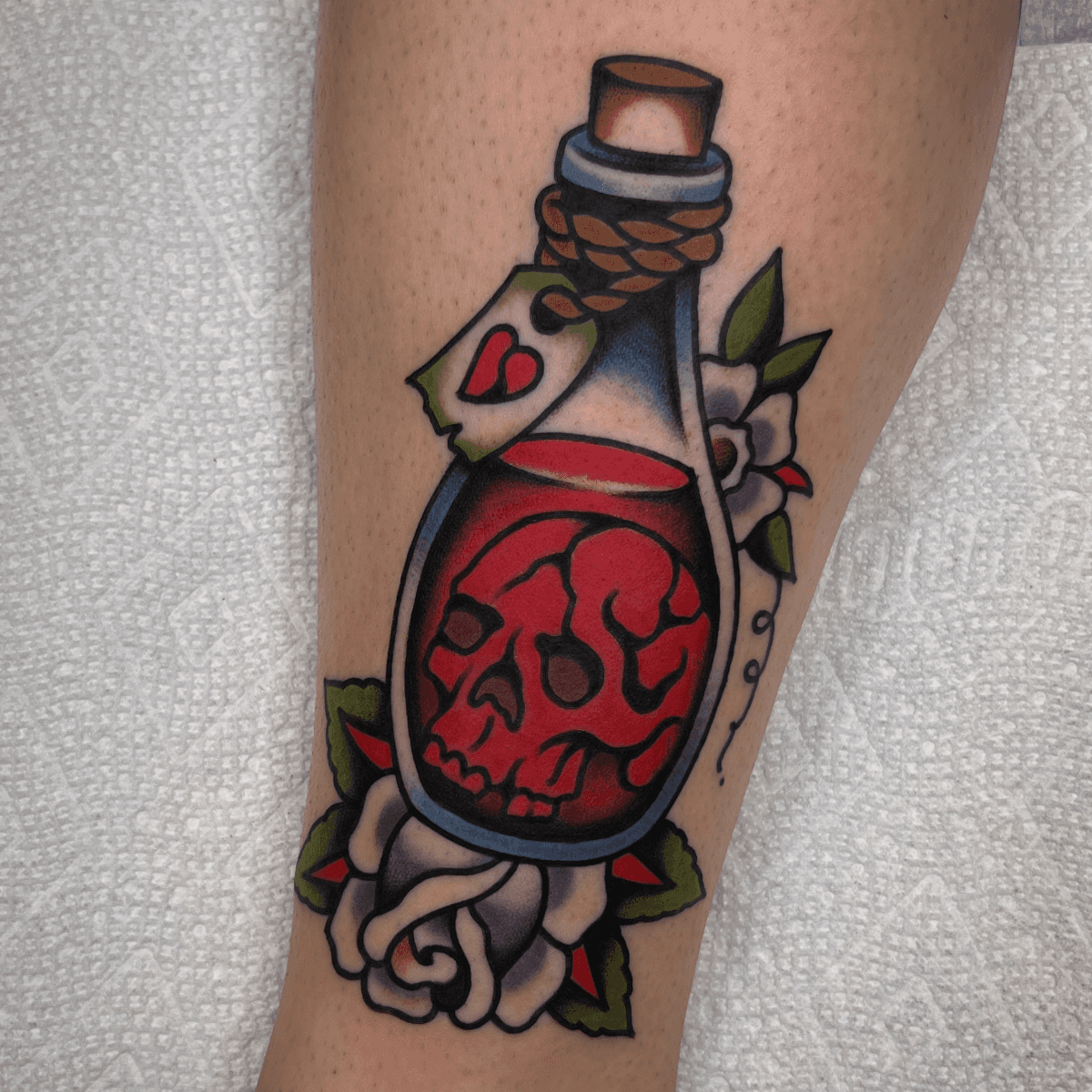 color tattoo of a skull in a bottle of red liquid