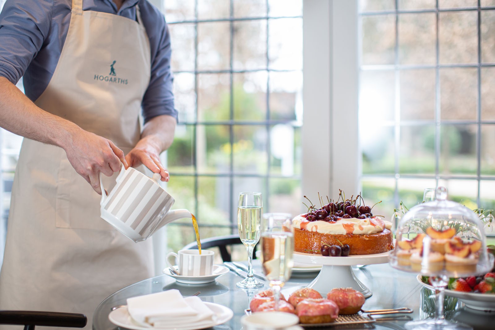 Hogarths Hotel staff pouring tea next to cakes and prosecco