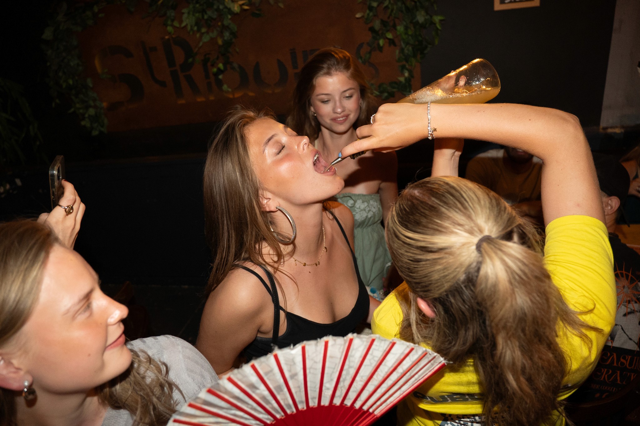 Young partygoers sharing a wild moment during a bar crawl in Nice as a guide pours a drink during a fun challenge capturing spontaneous energy laughter and the high intensity party atmosphere of an unforgettable nightlife experience on the French Riviera