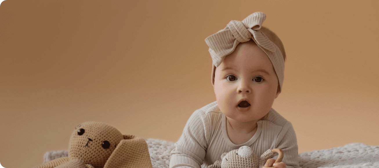 Baby next to a teddy bear, with brown background