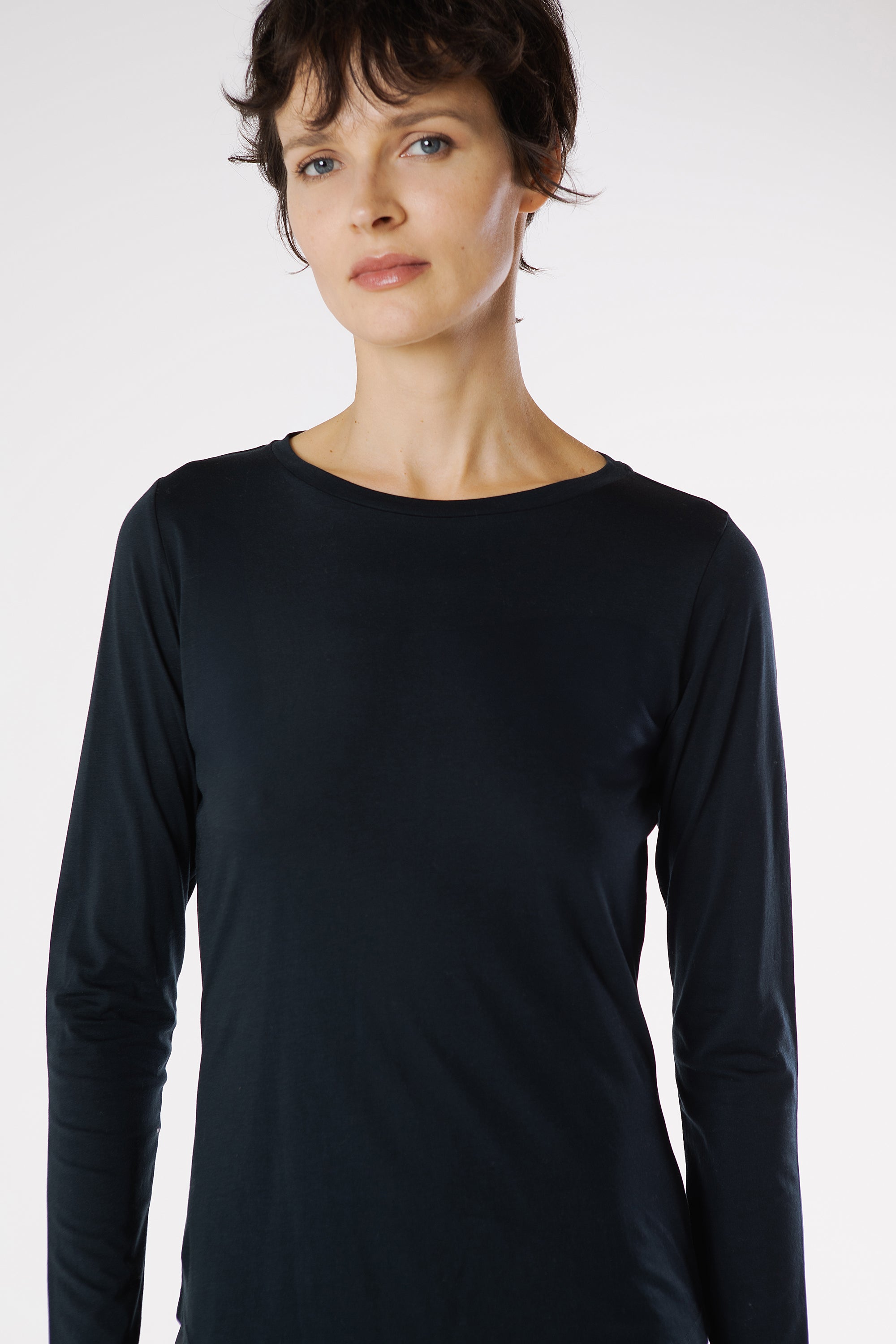 Woman wearing a black long-sleeve top against a white background