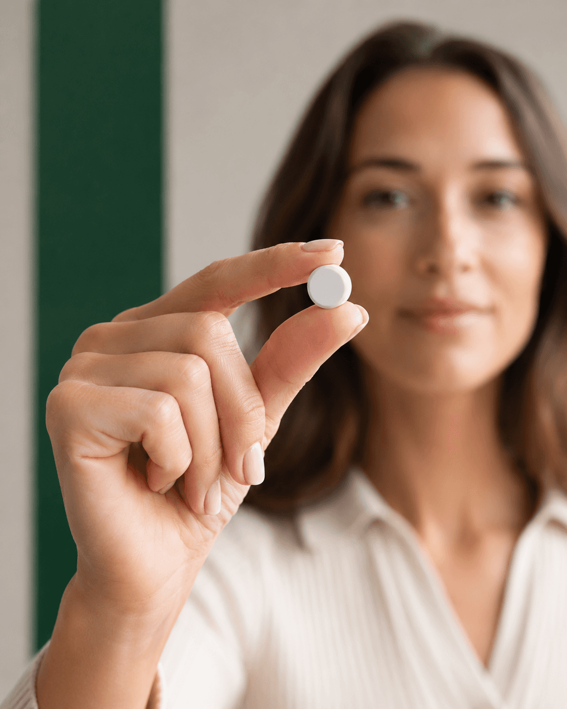 Woman holding up a small white weight-loss tablet