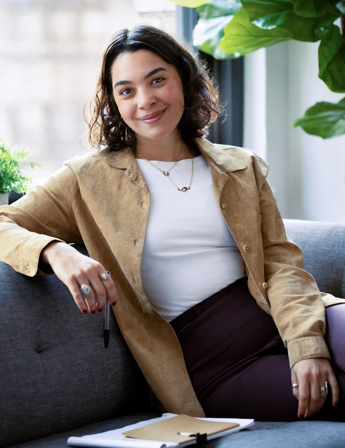photo of a therapist sitting in a modern inviting office space with couches and plants overlooking a big window framing the new york city skyline representing the affirming identity supporting lesbian affirming therapy found at expansive therapy.