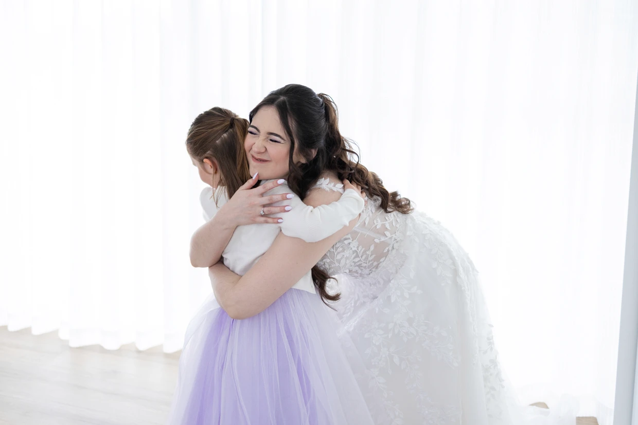 Bride hugging young flower girl