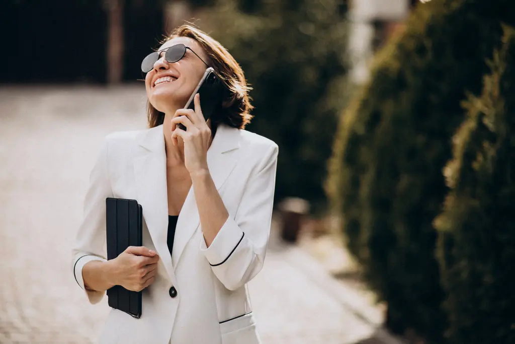 femme business joyeuse téléphone à la main avec veste blanche