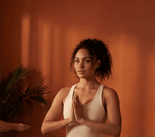 Diverse group practices yoga on cork yoga mats in a warm studio: warrior, tree, and seated poses.