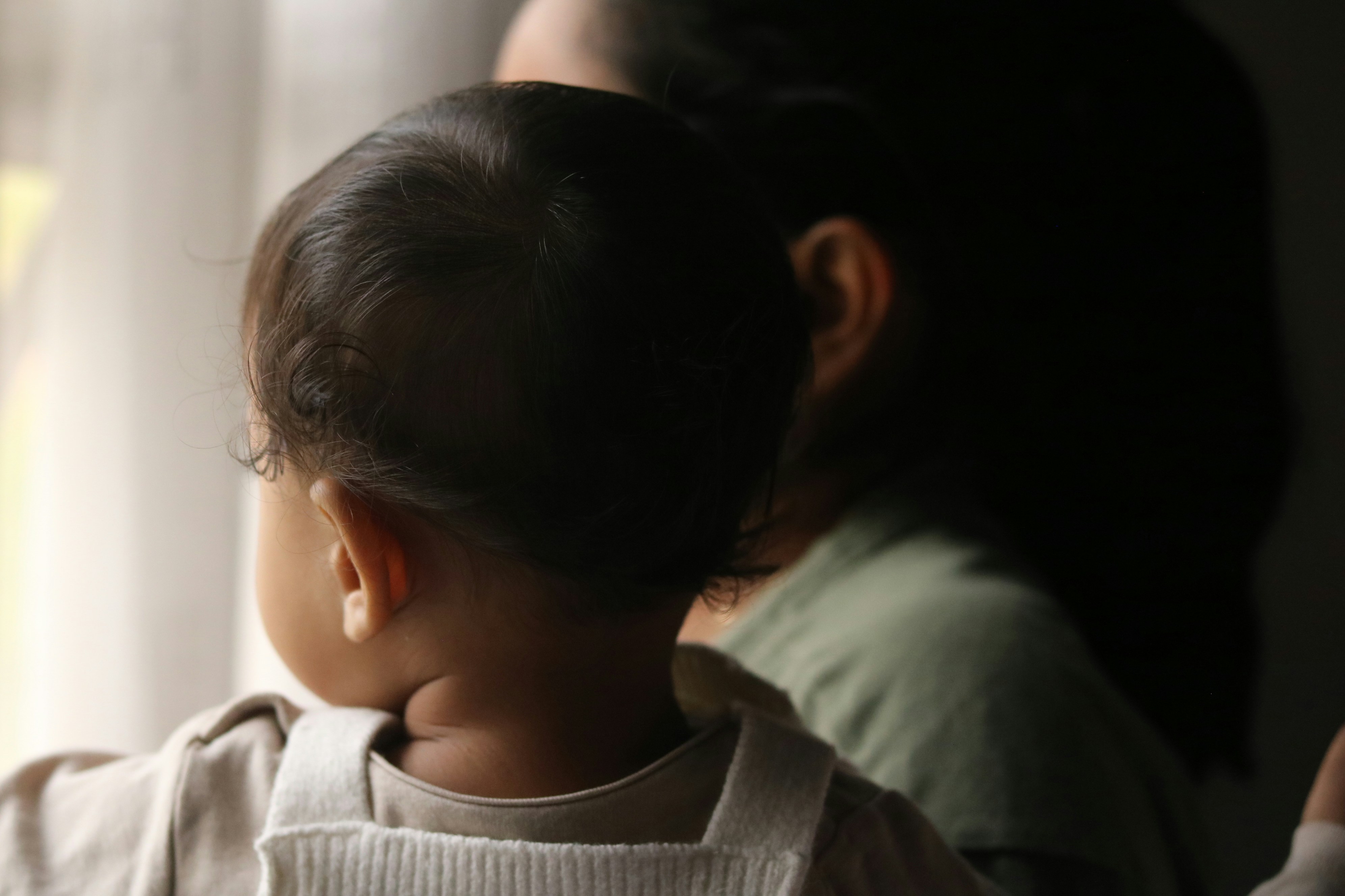 Mother holding a baby looking out window