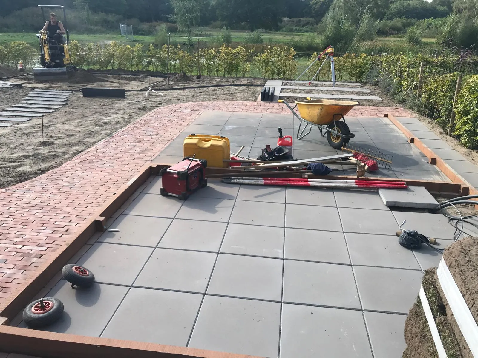 Net aangelegde straatstenen rond plantenborder, hout en grind — bestrating in Gorredijk / Friesland