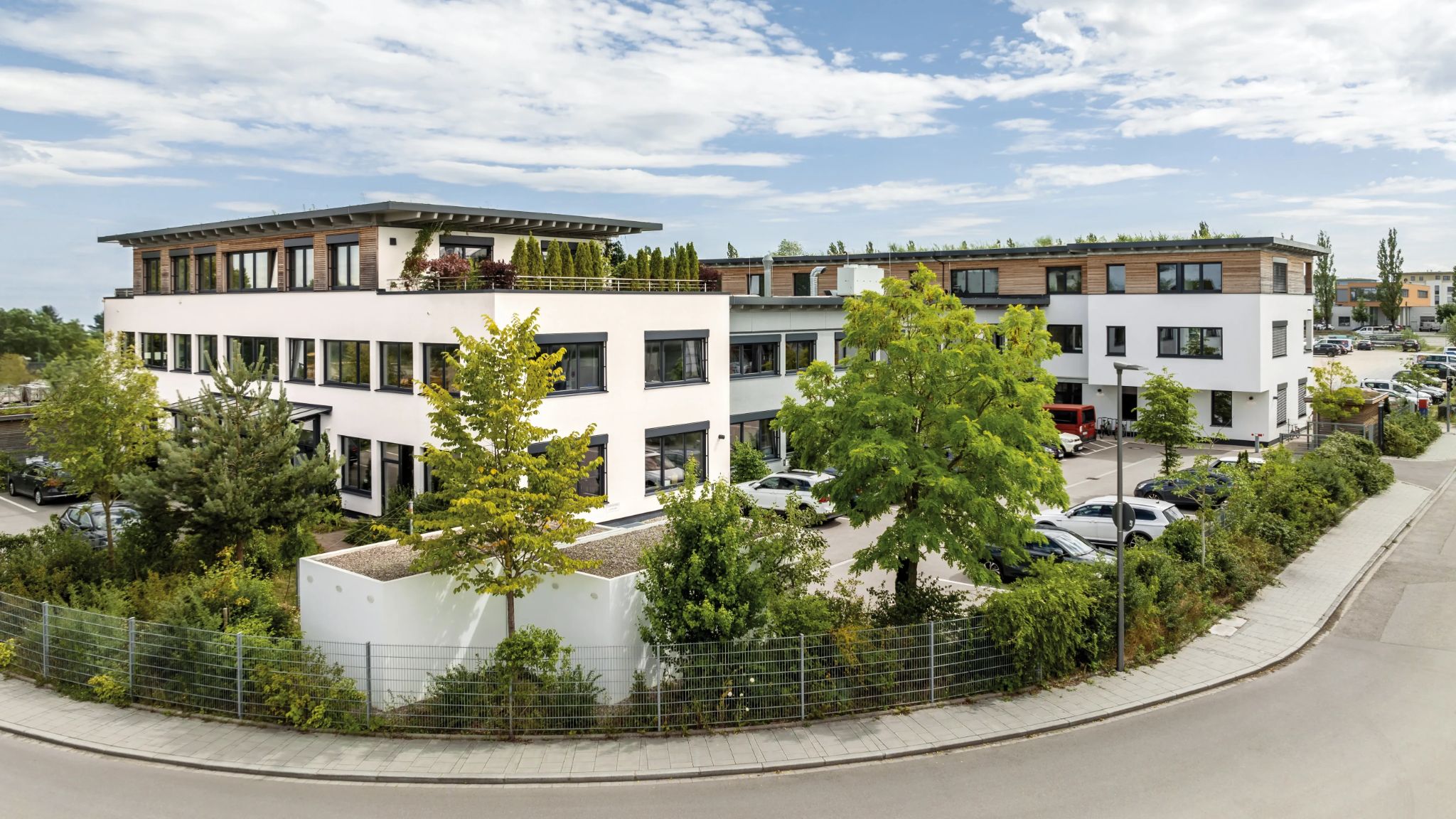 Blick auf modernes Bürogebäude mit leeren Parkplätzen davor.