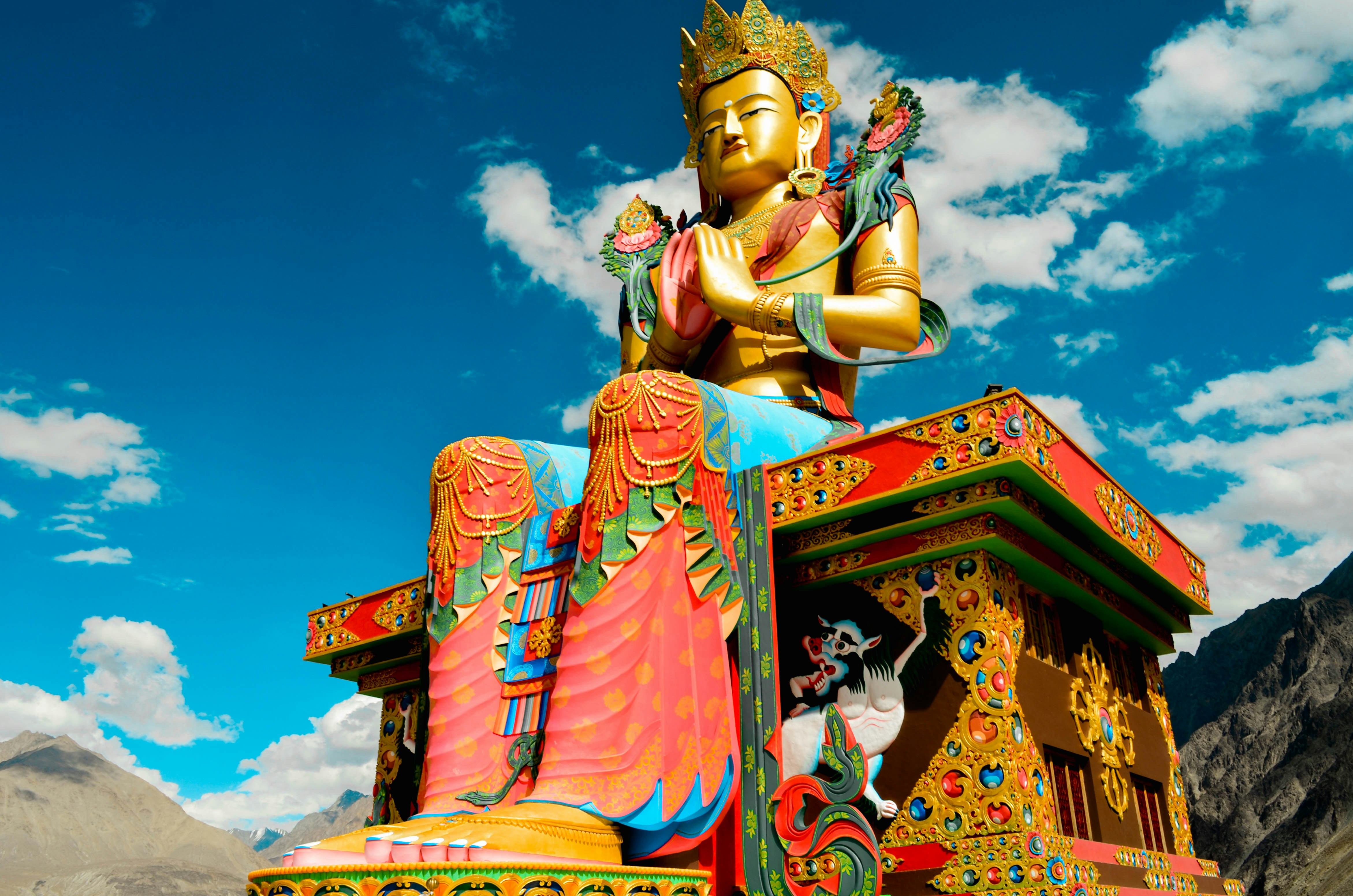 low angle photography of sitting Buddha statue under blue sky and white clouds at daytime