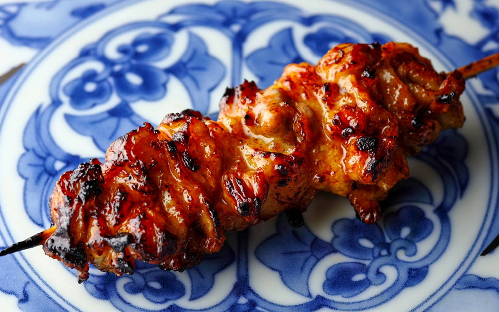 Yakitori chef grilling skewers at Yakitori Tsukiya in Tokyo, showcasing a 6/9-course meal experience.