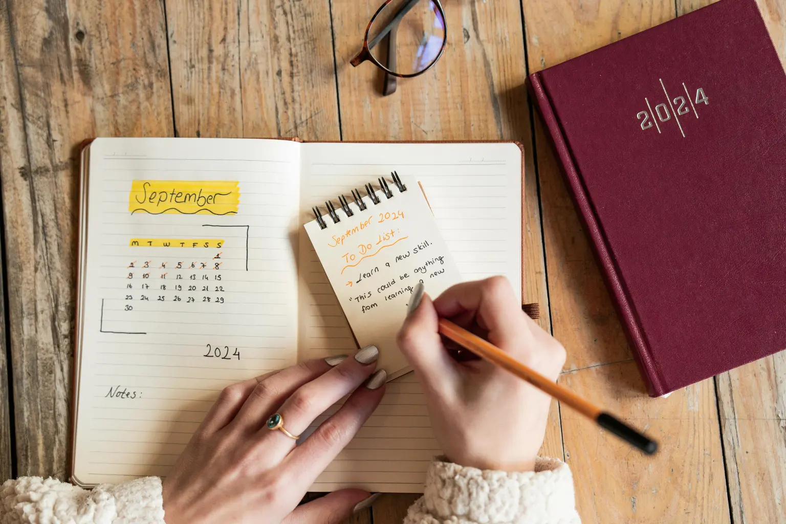 Calendar scheduling tools setup with a handwritten September planner and to-do list beside a red 2024 diary.
