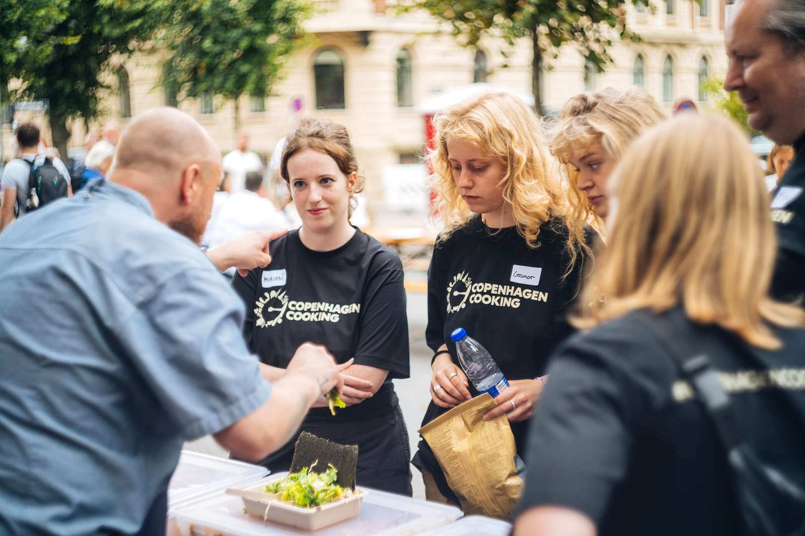 Glade frivillige serverer mad til gæster under Copenhagen Cooking festivalen.