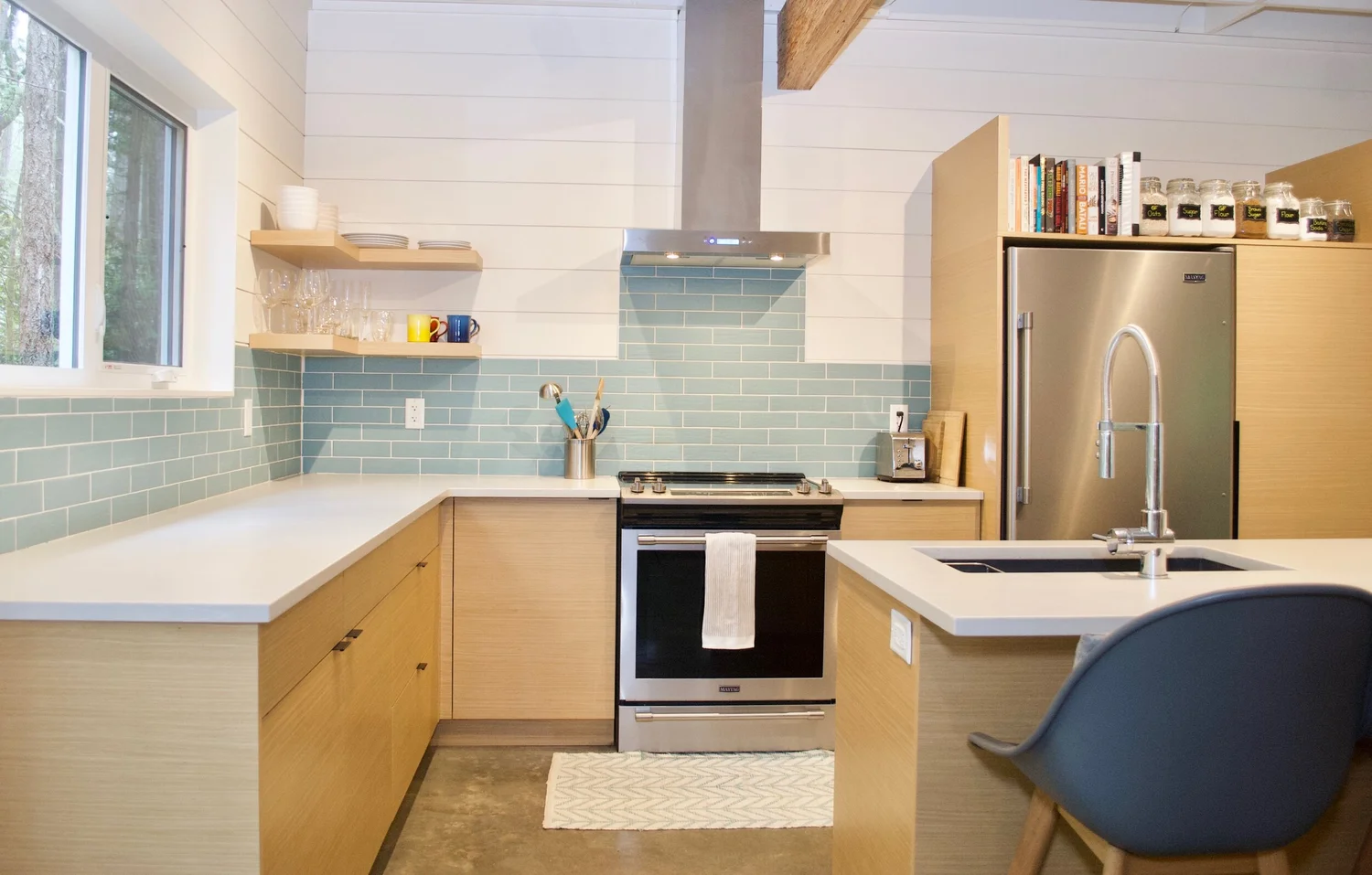 Modern two-story home with large glass windows, warmly lit interiors, and a balcony. Surrounded by trees and a manicured lawn at dusk. Cozy ambiance.