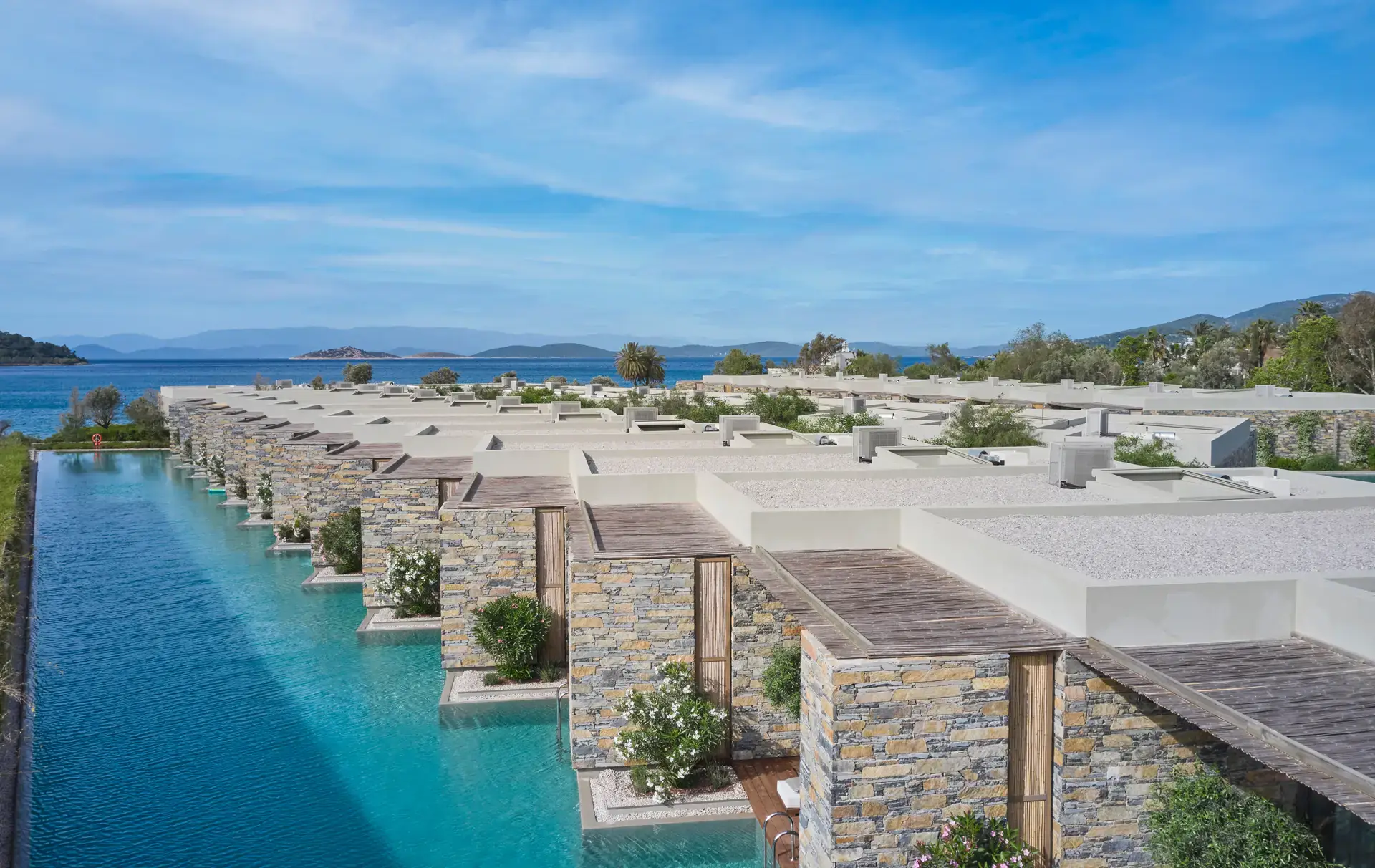 Aerial view of the rooms along the pool with the sea beyond