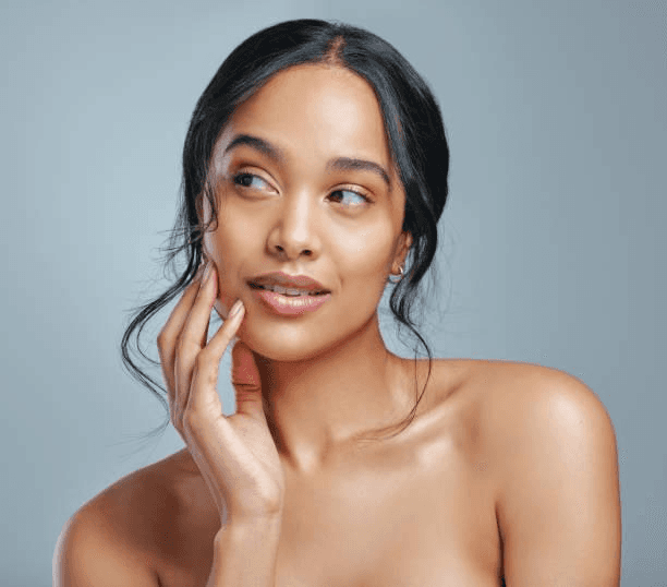 Close-up of a woman with under-eye gel patches, natural makeup, and smooth skin, against a neutral beige background