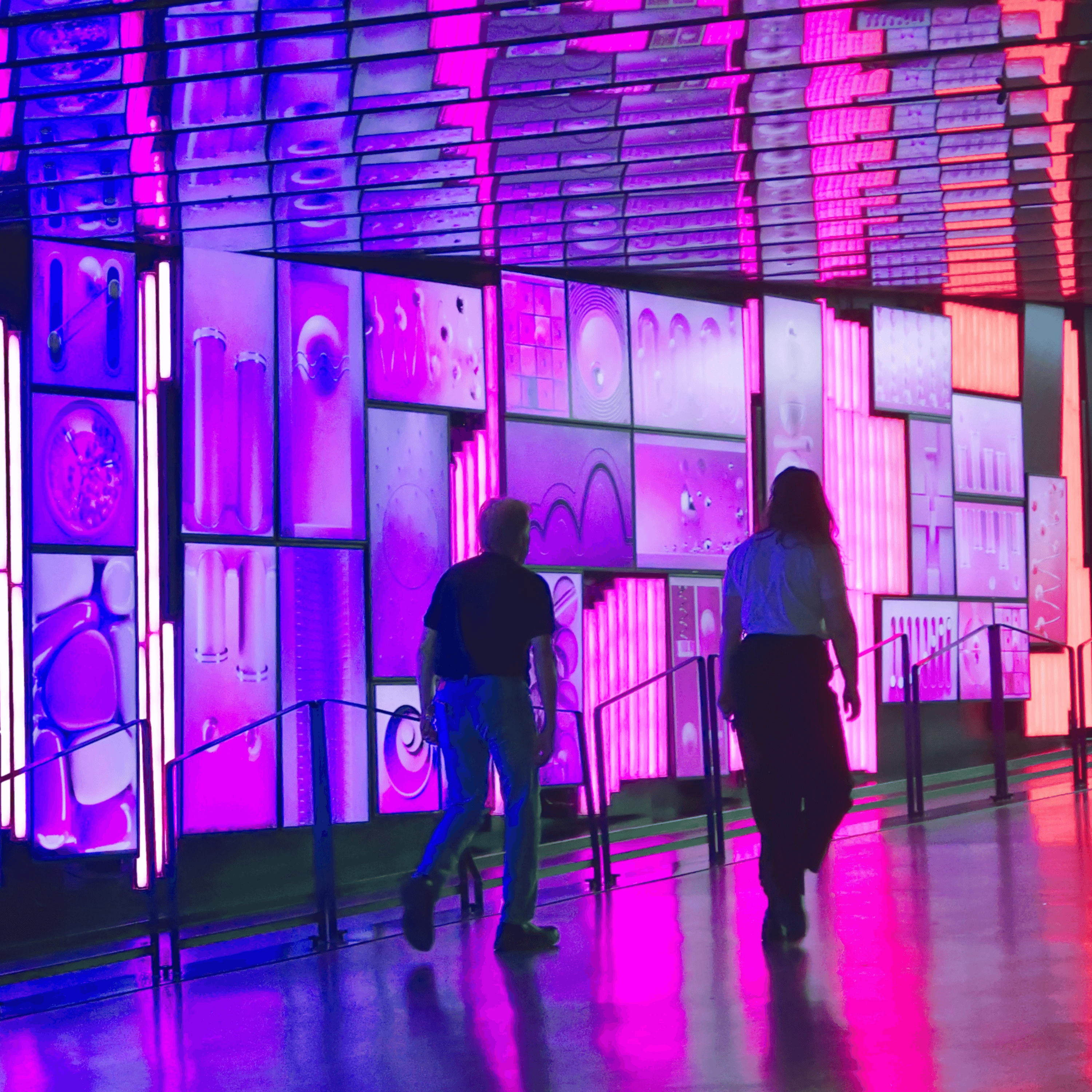 two people walking down a walkway next to a building