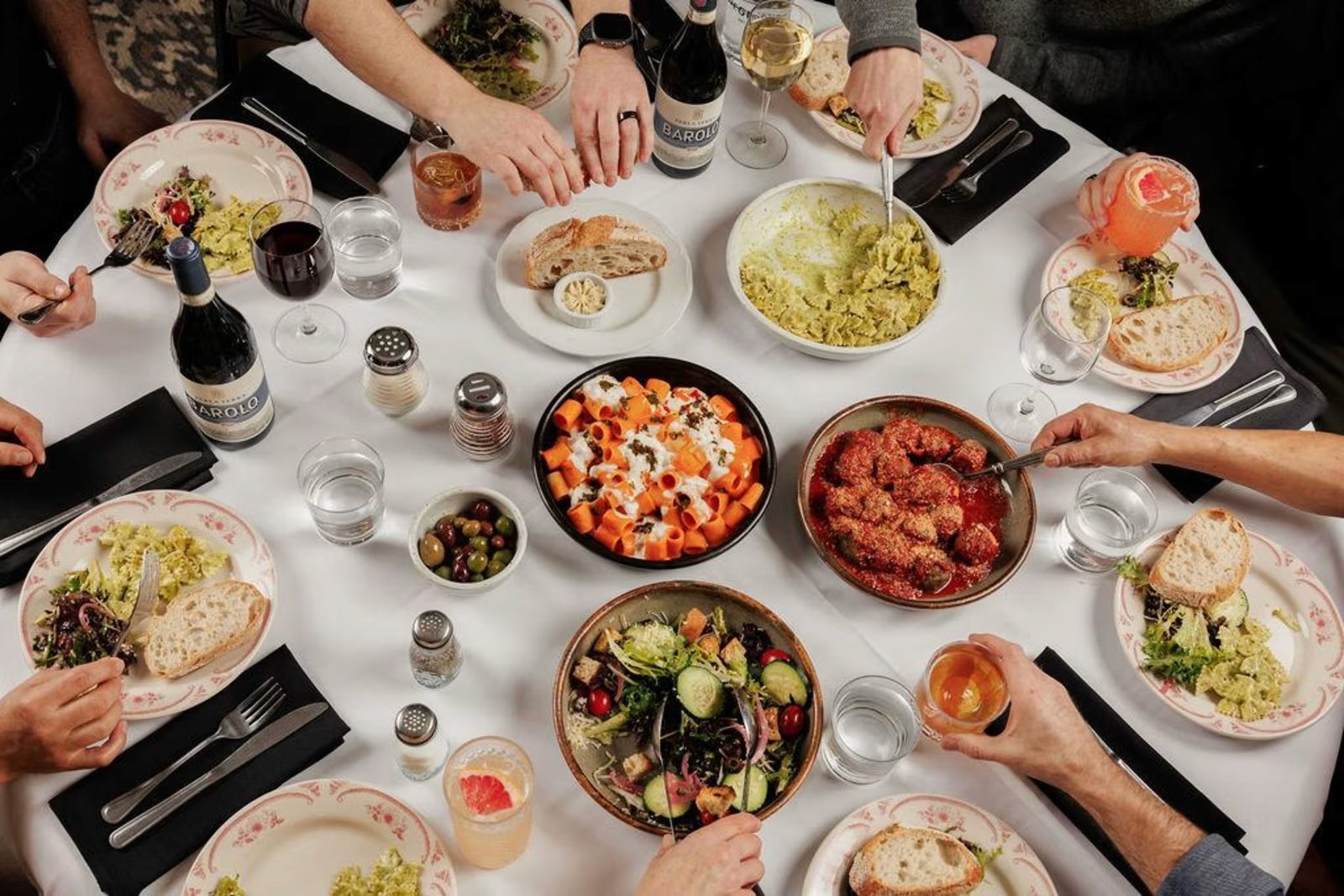 family style meal with meatballs, pesto pasta, rigatoni alla vodka and an old fashioned cocktail