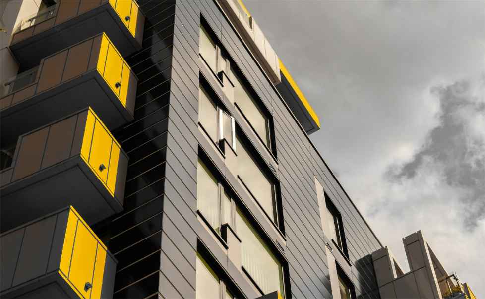 Apartment block with black cladding and yellow balconies