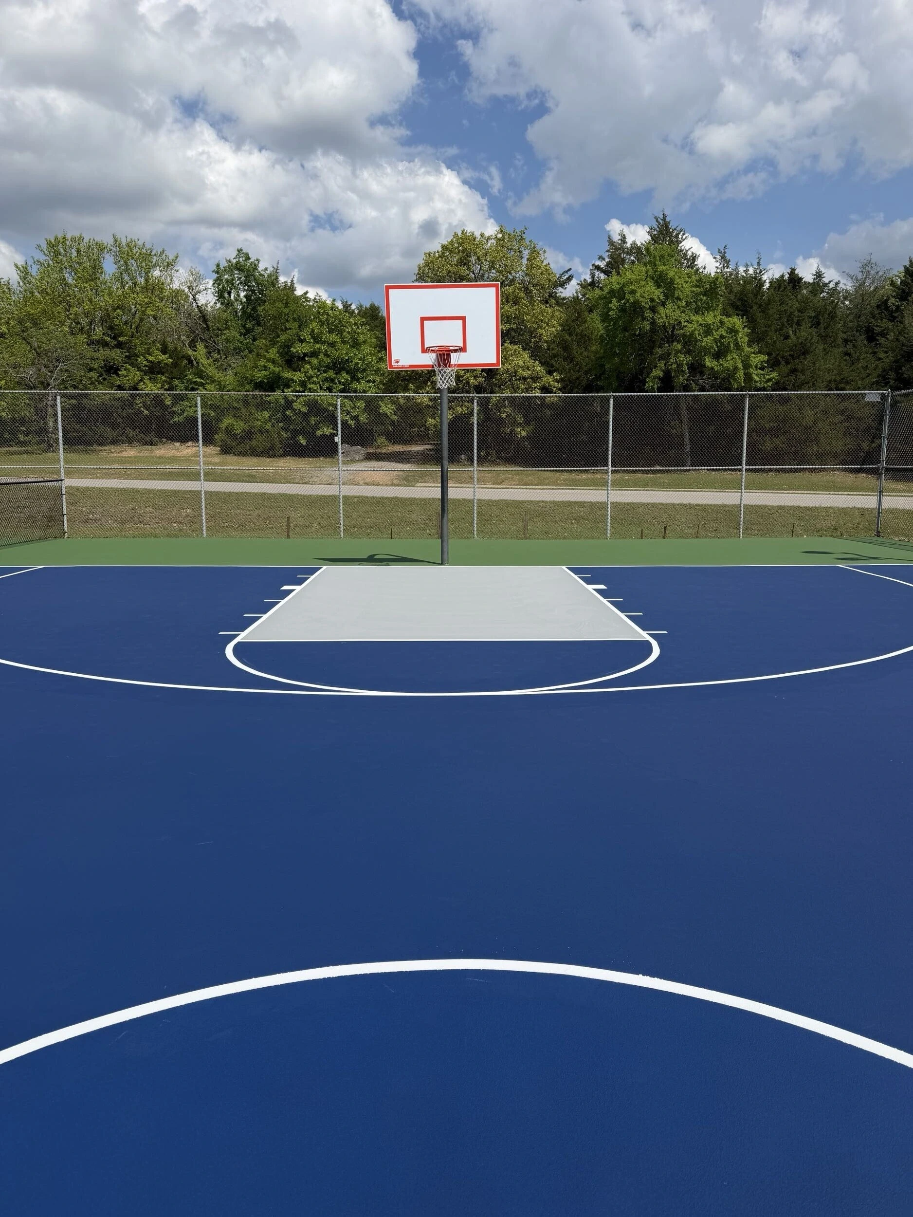 Resurfaced basketball court with navy blue coating and gray key at Bell Park in Greenwood, AR