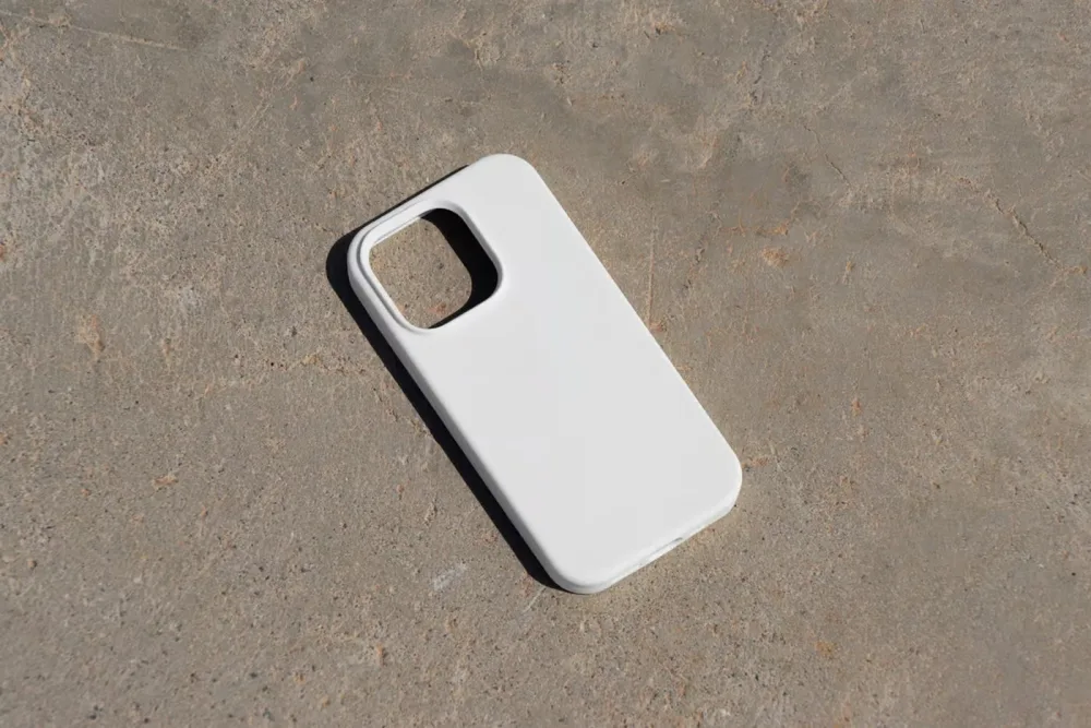 Green iPhone case mockup lying on a textured concrete surface, featuring a minimalist diagonal stripe pattern. Showcases the case design in natural sunlight with subtle shadows.