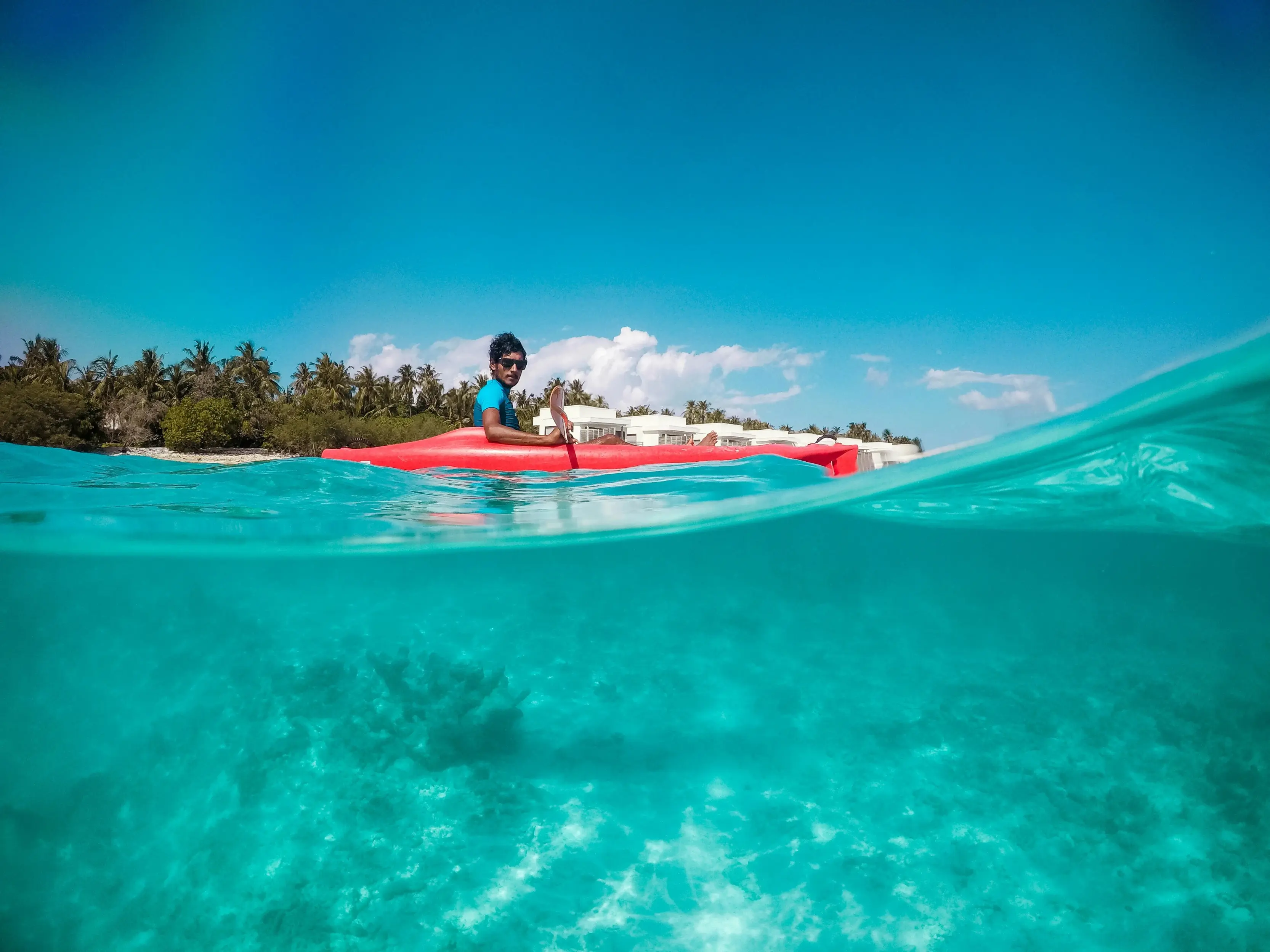 woman in black and pink bikini top riding white and red surfboard on blue sea during