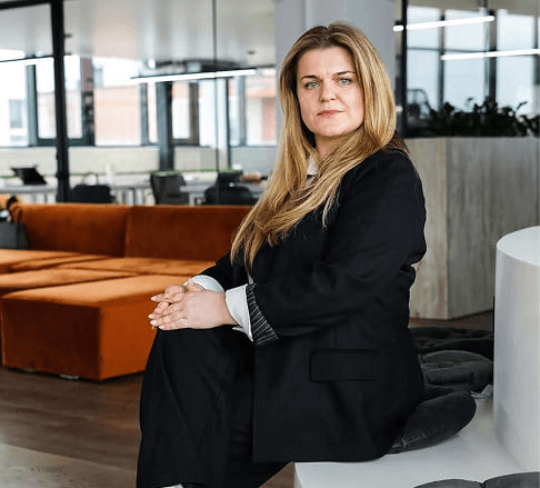 Black-and-white portrait of a man with an afro in motion, wearing a hoop earring and chain necklace, against a light gray background.