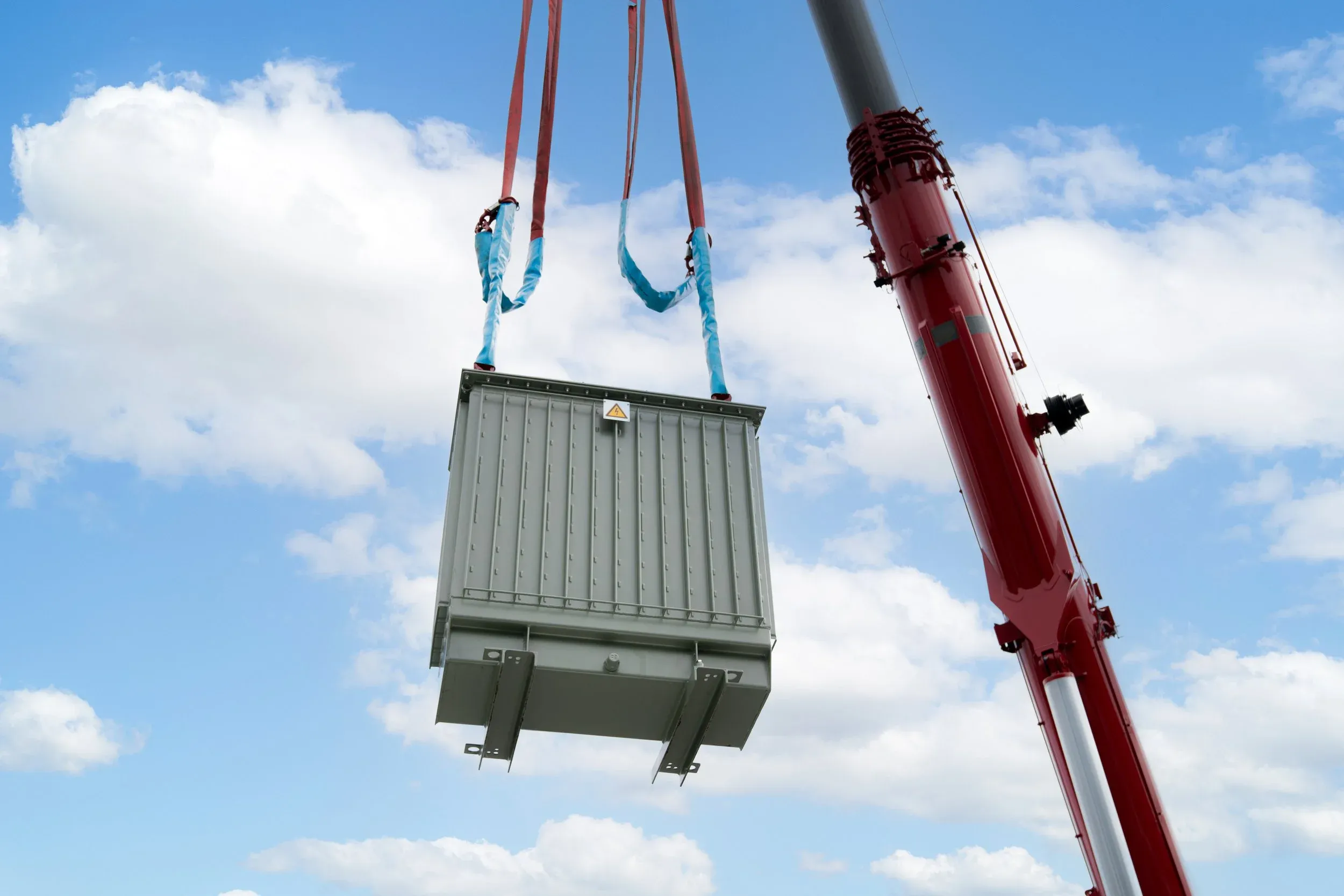 Kran hebt schweren Transformator im Freien hoch